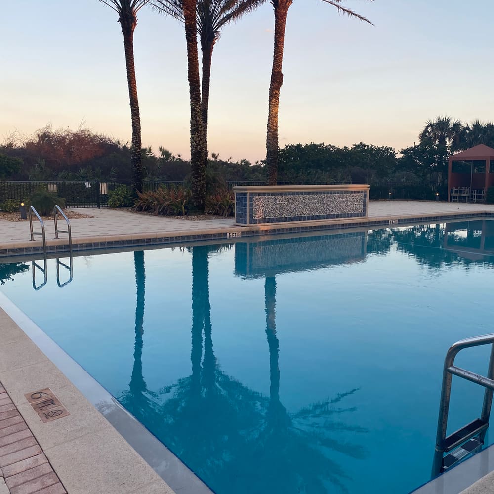 Community pool deck at dusk with tile accent wall